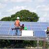 Des ouvriers installent des panneaux solaires sur une structure métallique en Tanzanie.