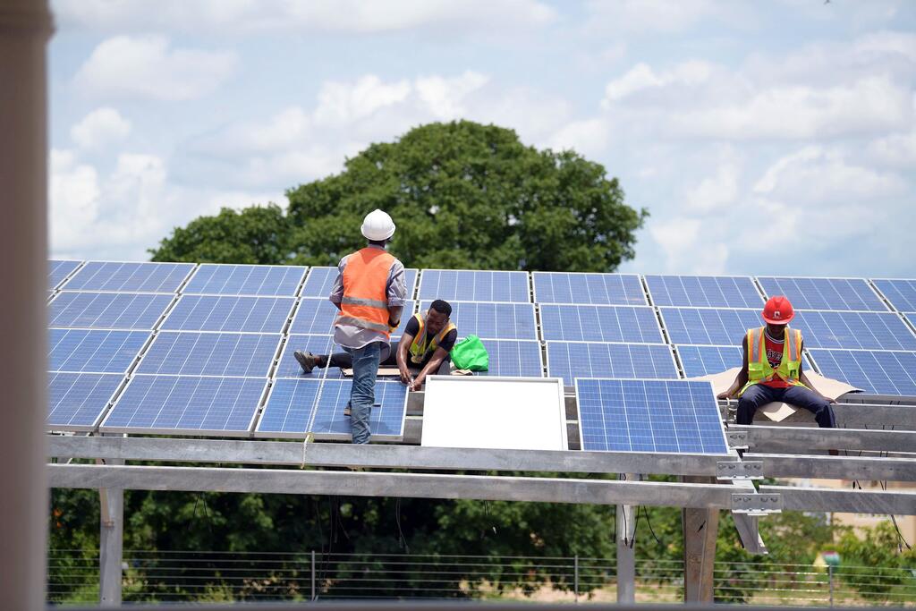 Des ouvriers installent des panneaux solaires en Tanzanie.