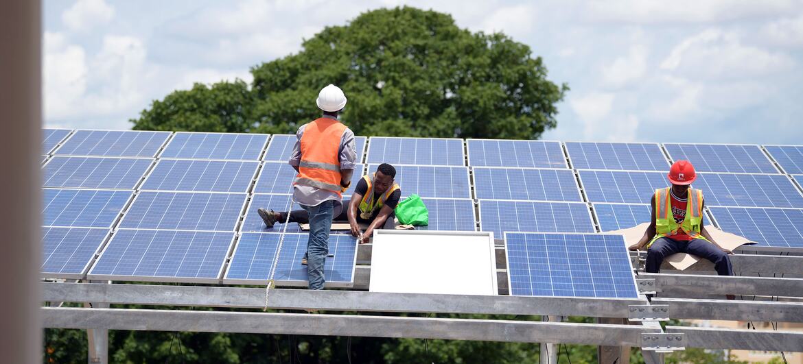 Des ouvriers installent des panneaux solaires sur une structure métallique en Tanzanie.