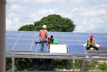 Des ouvriers installent des panneaux solaires sur une structure métallique en Tanzanie.