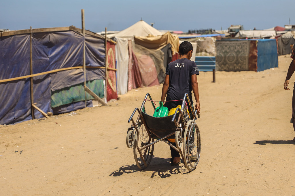 Un jeune homme transporte de l'eau dans un camp de tentes temporaire à Khan Younis, à Gaza.