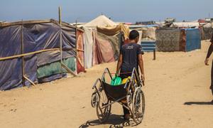 A young man drags water through a temporary tented camp in Khan Younis, Gaza.