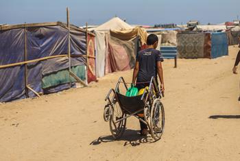 A young man drags water through a temporary tented camp in Khan Younis, Gaza.