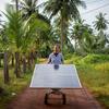 Un miembro de un grupo de mujeres agricultoras de Camboya hace rodar un panel solar por un sendero.