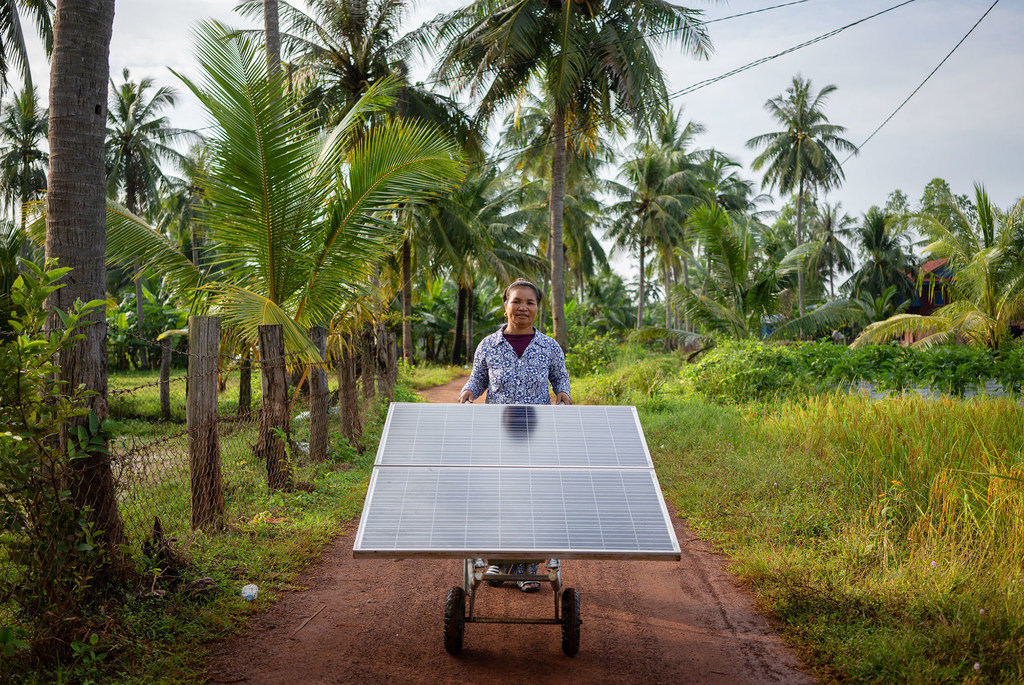 Un miembro de un grupo de mujeres agricultoras de Camboya hace rodar un panel solar por un sendero.