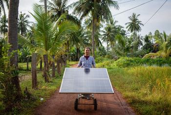 Un miembro de un grupo de mujeres agricultoras de Camboya hace rodar un panel solar por un sendero.