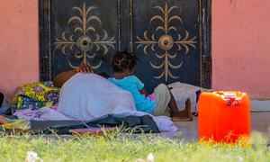 A mother and her child, displaced by gang violence, sleep on the bare floor of a school in Haiti.