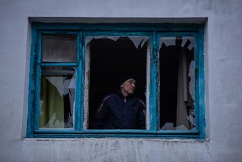 Mwanamume akikagua dirisha lake lililovunjwa baada ya kombora kutua karibu na nyumba yake huko Kherson, Ukrainia.