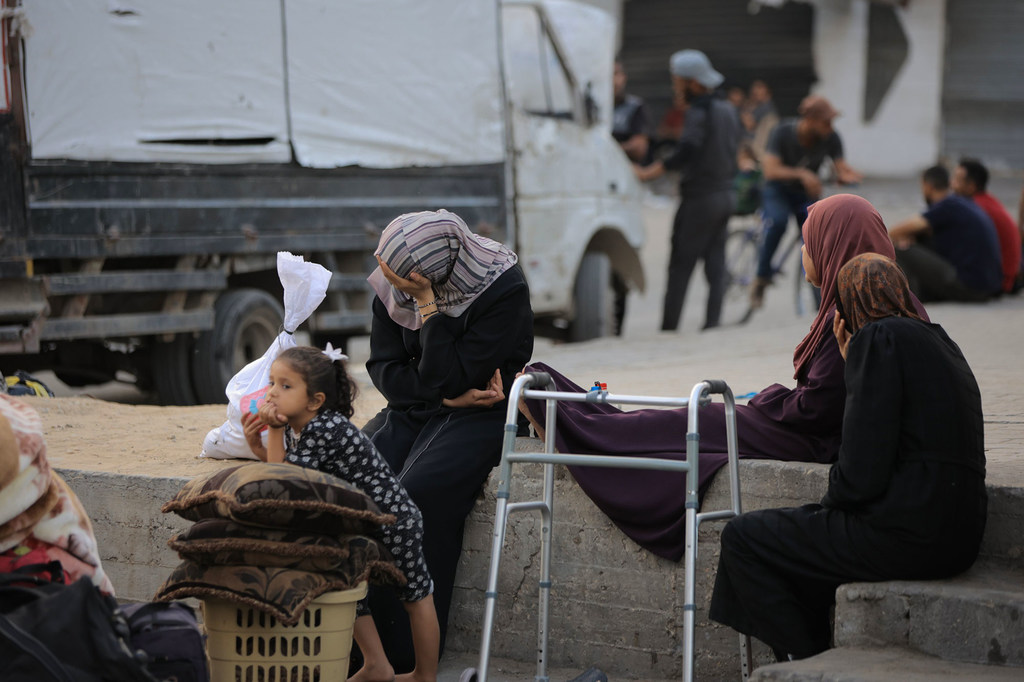 Des femmes qui ont fui leurs maisons à Gaza se reposent sur un mur.