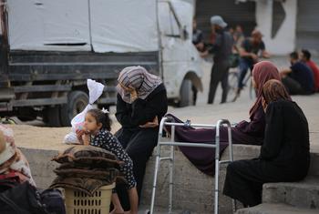 Mujeres que han huido de sus hogares en Gaza descansan sobre un muro.