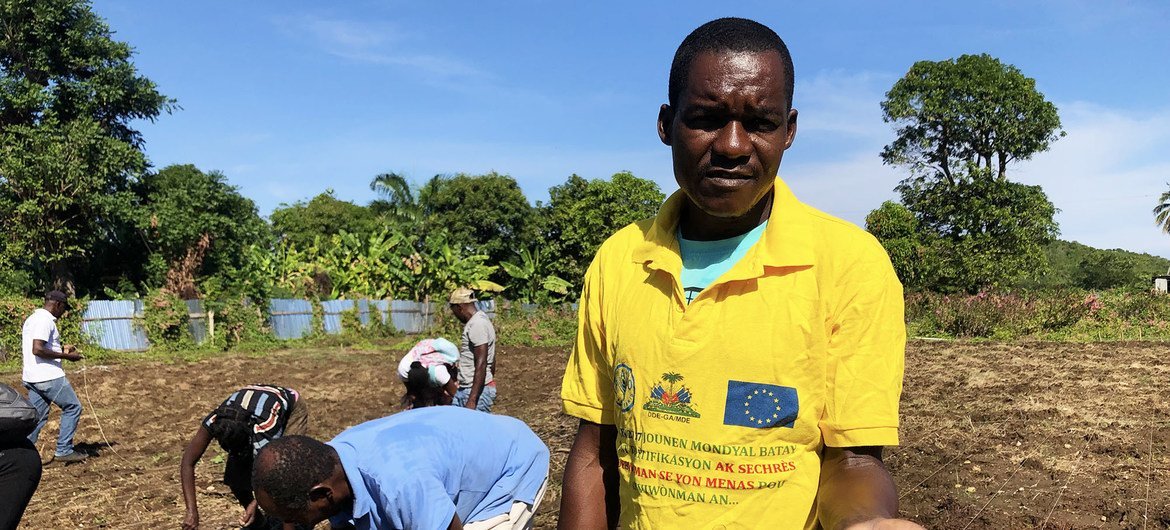 Farming association member, Pierre Ybert, works alongside other members planting black bean seeds.