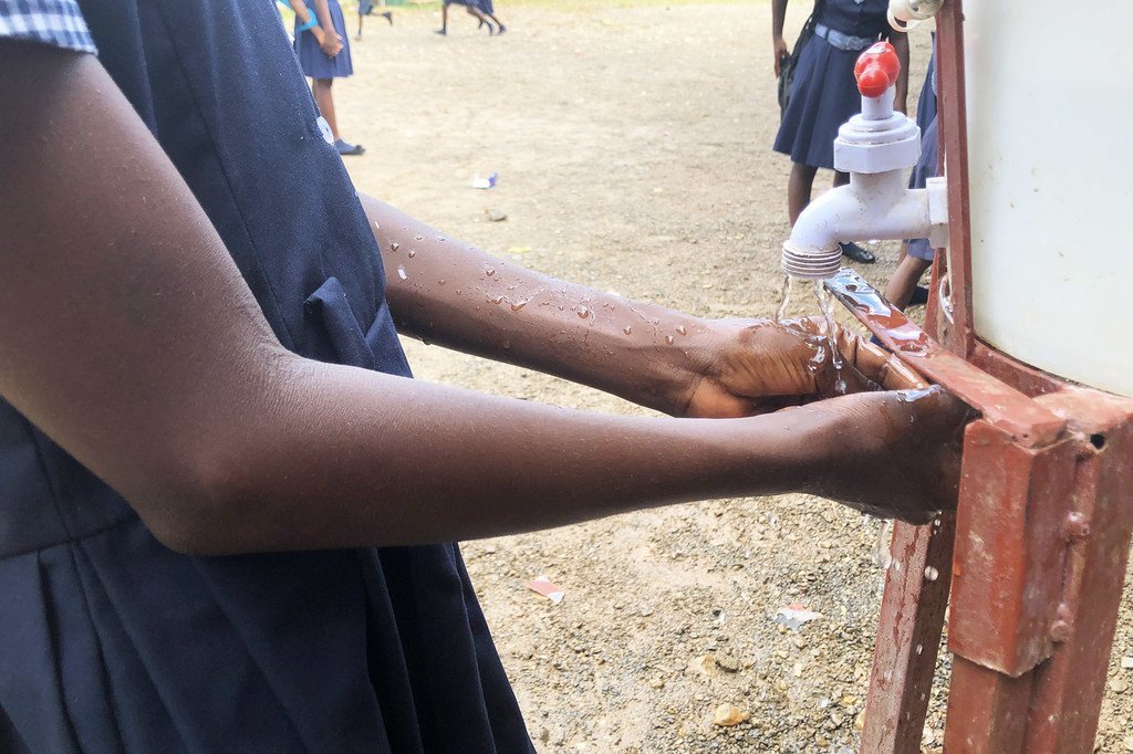 Una niñas se lava las manos antes de comer una comida escolar.