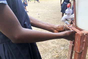 A child washes her hands before eating a school meal.