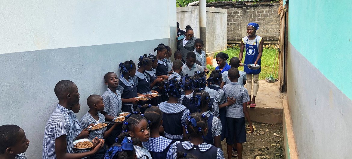 Des enfants haïtiens attendent de recevoir un repas scolaire fourni par le PAM.