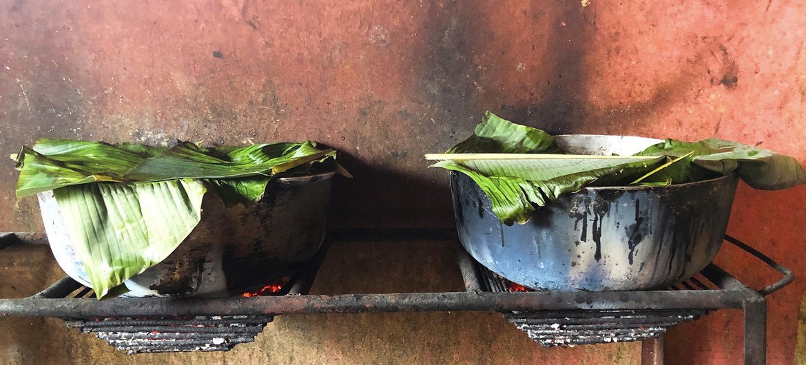 Banana leaves cover two pots of beans and wheat, school meals for over 300 children.