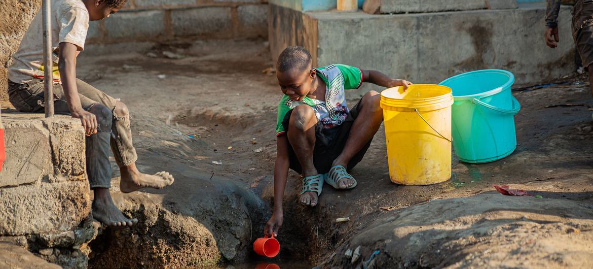 Um menino tira água de uma vala