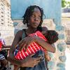 Mwanamke aliyekimbia makazi yake Tamaila Augustin kutoka Haiti akimbeba mtoto wake uani.