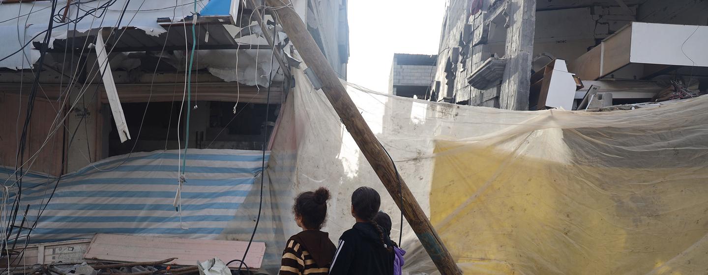 Des enfants de Khan Younis s'arrêtent pour regarder les dégâts alors qu'ils sont à la recherche d'eau.