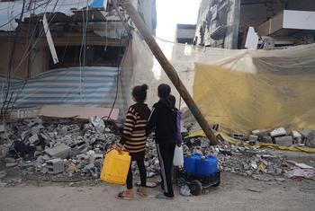 غزہ کے علاقے خان یونس میں بچے پانی کی تلاش میں جاتے ہوئے بمباری میں تباہ ہوئے گھروں کو دیکھ رہے ہیں۔