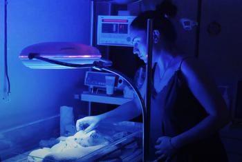 A mother gently touches her newborn baby inside an incubator at the Kherson City Perinatal Centre in Ukraine, supported by UNFPA.