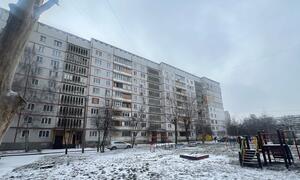 Damaged apartment buildings in Saltivka, Kharkiv, Ukraine, with snow-covered ground and a playground in the foreground.