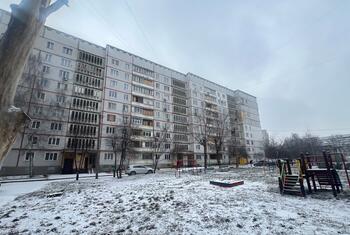 Damaged apartment buildings in Saltivka, Kharkiv, Ukraine, with snow-covered ground and a playground in the foreground.