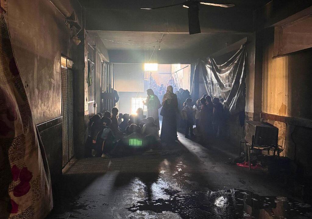 Les enfants se rassemblent dans un couloir mal éclairé et endommagé d'une école à Gaza, pour apprendre dans un espace d'apprentissage temporaire de l'UNRWA.