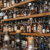 Una vista de cerca de numerosas botellas de alcohol colocadas en estantes de madera en un bar.