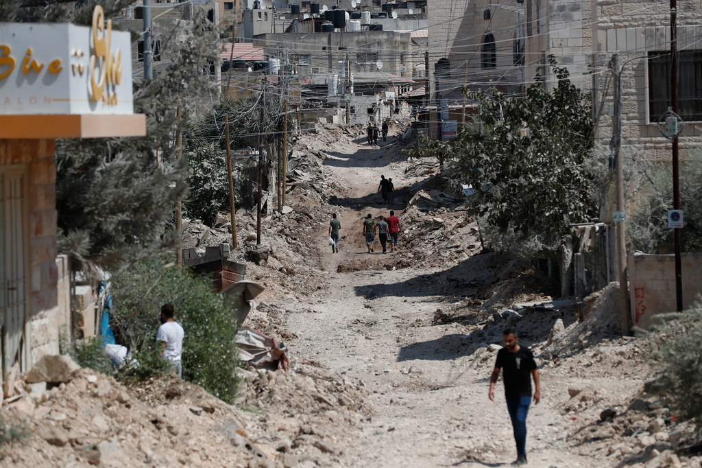 Des gens marchent à travers les décombres de routes et de bâtiments détruits dans le camp de réfugiés de Jénine, dans le nord de la Cisjordanie.