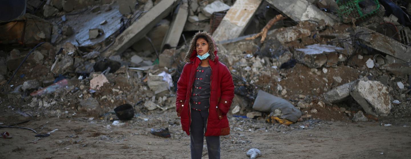 A twelve-year-old girl stands in front of her destroyed house in Rafah city, southern Gaza.