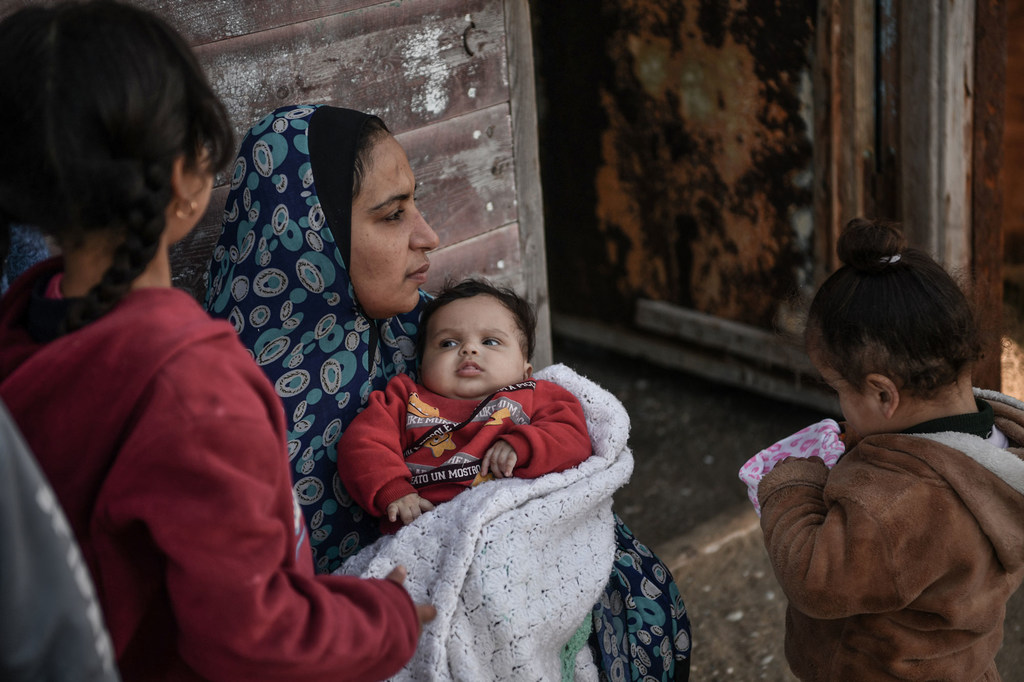 أم وأطفالها أجبروا على إخلاء منزلهم في غزة ويعيشون الآن في مخيم للاجئين في رفح.