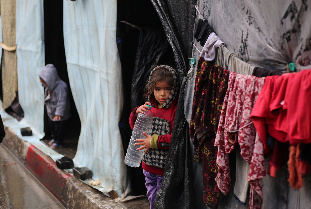 A girl stands in front of her shelter in the city of Rafah.