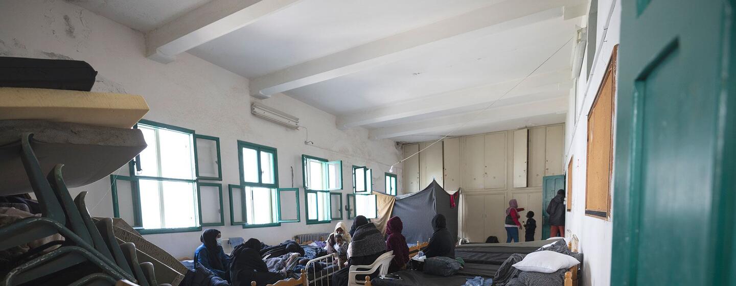 Une pièce bondée à l'intérieur d'un refuge temporaire au Liban, montrant plusieurs personnes, y compris des femmes et des enfants, reposant sur des matelas au sol.