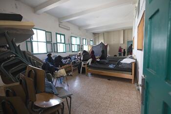 Une pièce bondée à l'intérieur d'un refuge temporaire au Liban, montrant plusieurs personnes, y compris des femmes et des enfants, reposant sur des matelas au sol.