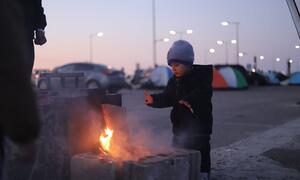 Un niño pequeño se calienta las manos sobre un pequeño fuego construido con bloques de hormigón en un estacionamiento, con tiendas de campaña y otras personas desplazadas visibles en el fondo en Beirut, Líbano, el 9 de marzo de 2026.