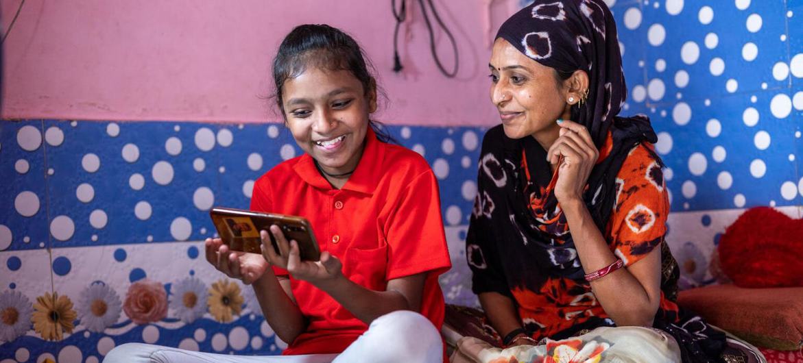 Una madre ayuda a su hija con sus estudios en línea mientras las escuelas están cerradas durante la pandemia del COVID-19 en la India. (archivo)