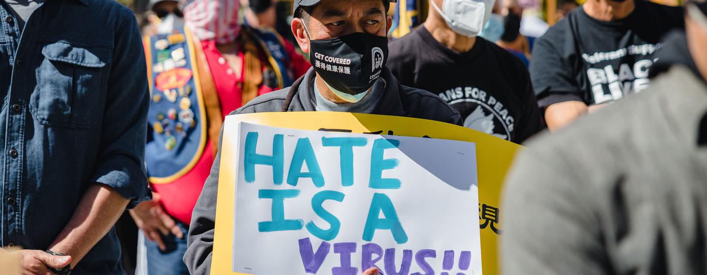Des manifestants aux États-Unis brandissent une affiche « la haine est un virus ».