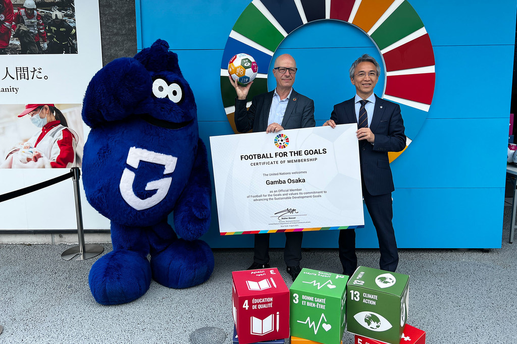 联合国的纳赛尔（左）和大阪钢巴队的伊藤慎次一起庆祝这家日本俱乐部加入“足球推动目标”倡议。
