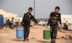 Two children collect drinking water in a camp for displaced people in Idlib, Syria.