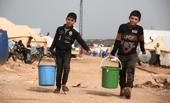 Two children collect drinking water in a camp for displaced people in Idlib, Syria.