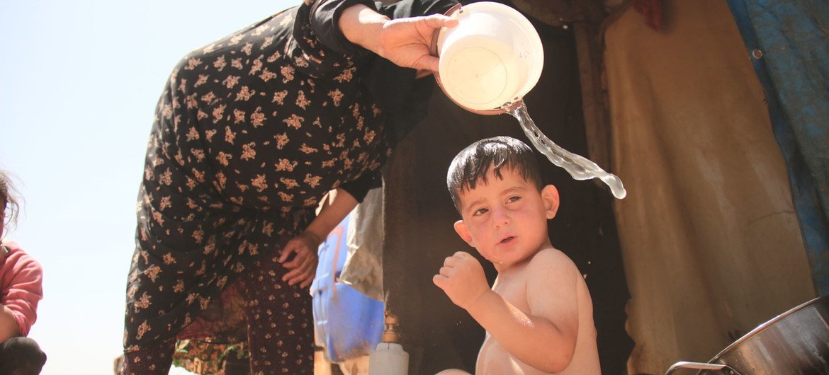 جدة تقوم بتغسيل حفيدها في أحد مخيمات النازحين بريف إدلب.