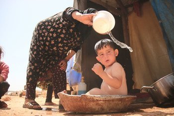 جدة تقوم بتغسيل حفيدها في أحد مخيمات النازحين بريف إدلب.