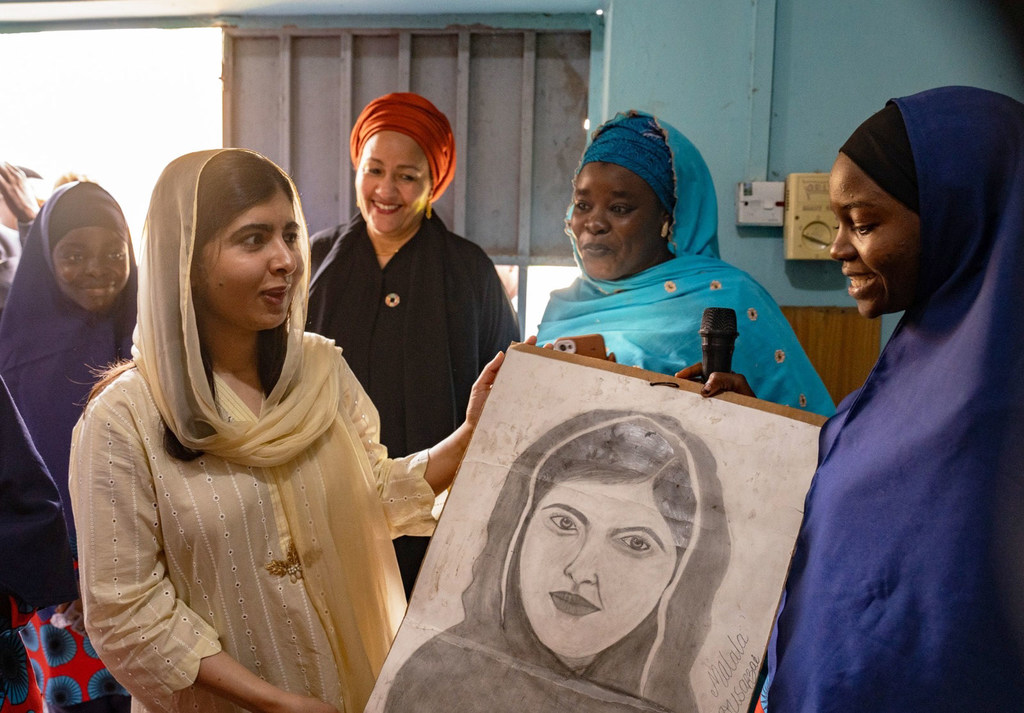 Malala Yousafzai is presented with a portrait by students of the Lafiya Sariri Learning Centre students in Borno state, North-eastern Nigeria. Deputy Secretary-General Amina J. Mohammed looks on. 