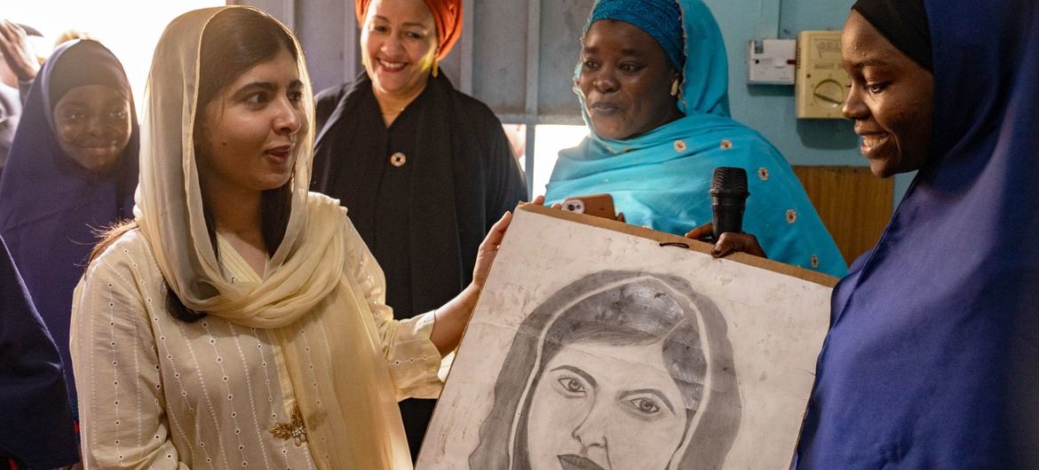Malala Yousafzai is presented with a portrait by students of the Lafiya Sariri Learning Centre students in Borno state, North-eastern Nigeria. Deputy Secretary-General Amina J. Mohammed looks on. 