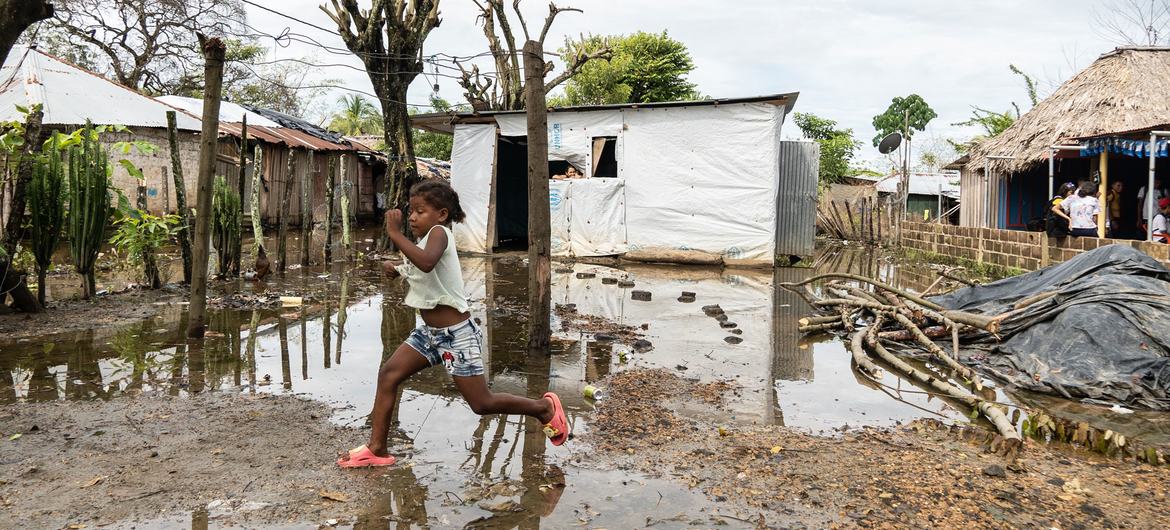 Una niña corre a través de un pueblo inundado en Colombia, pasando junto a refugios improvisados.