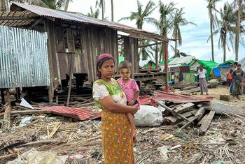 ایک ماں اپنے بچے کے ساتھ سمندری طوفان موچا میں تباہ ہو جانے والے اپنے گھر کے پاس کھڑی ہے (فائل فوٹو)۔