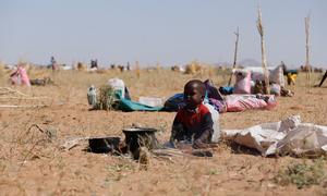 A child sits next to a stove in Tawila after his family fled El Fasher. They have faced 