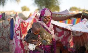 A woman walks through a camp for people who fled violence in North Darfur.