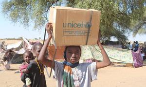 A woman who fled El Fasher in Darfur carries aid in a displacement camp in Tawila.