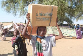A woman who fled El Fasher in Darfur carries aid in a displacement camp in Tawila.